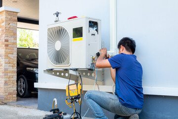 Obraz premium Male technician installing outdoor unit of air conditioner to cool the household in the summer. air compressor, electronic, hot summer, high temperature, Tropical countries