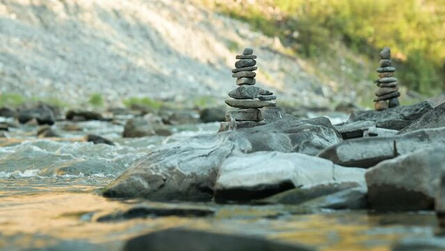 Balanced stone towers on fast mountain river. Symbol of balance, meticulous work of balancing stones one on another