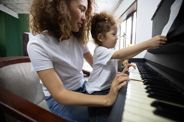 Funny Girl amd Happy Mother Play on Piano Together. Hobbies For Mother and Young Daughter. Happy...