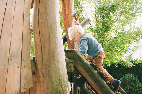 Outdoor portrait of adorable 4 - 5 year old little boy playing on playground