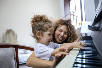 Funny Girl amd Happy Mother Play on Piano Together. Hobbies For Mother and Young Daughter. Happy...
