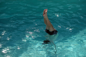 Man in a swimming pool exercising an underwater handstand