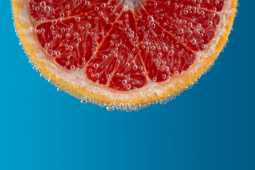 Close up view of a slice of grapefruit in soda water with bubbles.