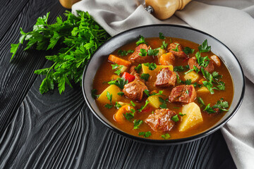 fragrant thick goulash soup on a black wooden rustic background