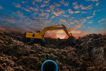 Crawler excavators is digging in the construction site pipeline work ,on a sunset background