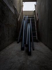 Metal pipes laying on wooden stairs, ready to be picked up to install into the building, blue...