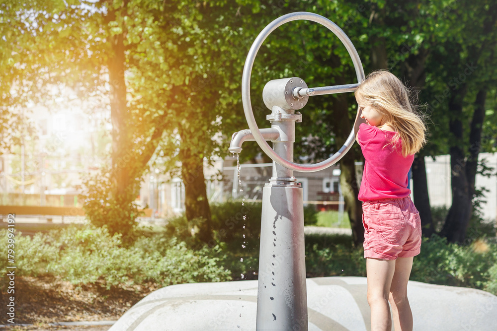 Wall mural water well in modern water playground. little child pumps hand pump in nature in green city. educati