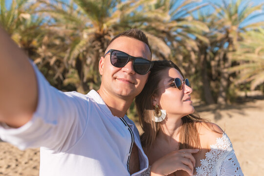Young happy couple taking selfie on a palm beach . Summer vacations concept.
