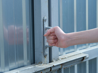 A person opening a metal gate. Close up.