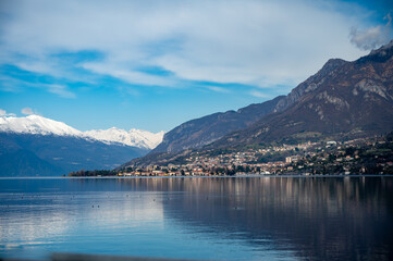 Driving car along shores of Lake Como in Northern Italy, spring sunny days, views of alpine mountains, water and villages - obrazy, fototapety, plakaty