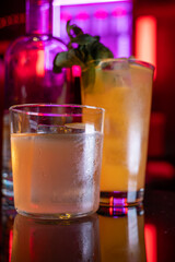 Whiskey and rum colorful cocktails served with ice cubes on black table in dark cocktail bar in Italy