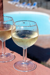 Glasses of cold white wine on roof terrace served outdoor in Corralejo, Fuerteventura in sunny day, pool with blue water