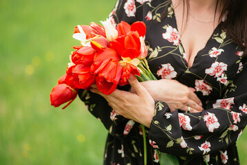 woman holding a bouquet of red tulips in the park 