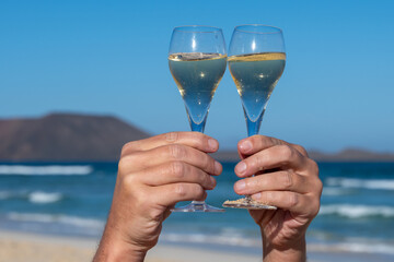 Pouring a glass of champagne on vacation, south of Fuerteventura, Canary islands, blue ocean, mountains