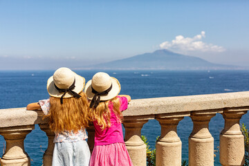 Sorrento, Italy - August 15th, 2023. Two tourist gitls in heats looking at Mount Vesuvius from...