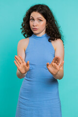 Young woman say No hold palm folded hands in stop gesture, warning of finish, prohibited access, declining communication, body language, danger. Girl on blue background. Lifestyles. Vertical