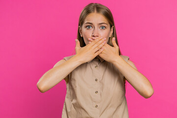 I will not say anything. Frightened woman closing mouth with hands, looking intimidated scared at camera, gestures no, refusing to tell terrible secret, unbelievable truth. Girl on pink background