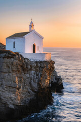 Fototapeta na wymiar Perched atop a rugged cliff overlooking the endless ocean, a quaint small church stands as a serene sanctuary. 