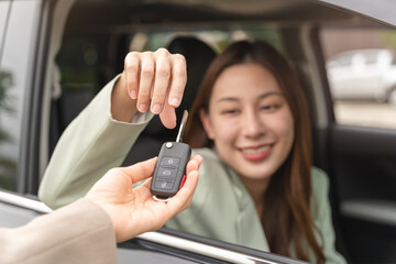 transportation rental automotive business concept. Close up hands of rental auto agent giving car remote key to client to travel sightseeing.