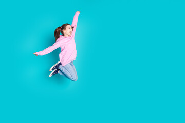 Full length photo of lovely little girl jump flying have fun dressed stylish pink garment isolated on aquamarine color background