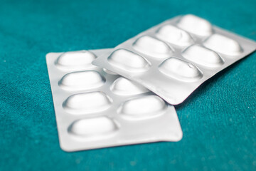 Two pill blister packs on green surface in medical setting
