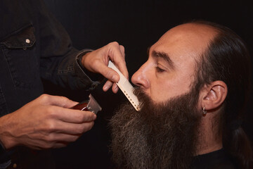A barber styling a recently cut mustache with a comb