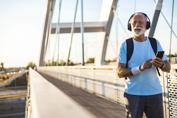 Senior male selecting song from playlist on technology.