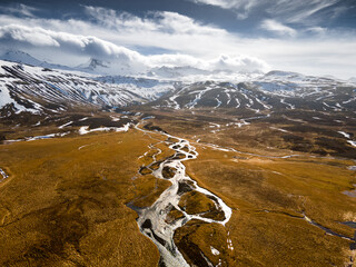 Aerial view of Icelandic highlands landscape with river and snowy mountains and clouds 1
