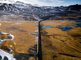 Aerial view of an asphalt singe lane road across Icelandic highlands with a river crossing and...