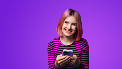 Excited surprised shocked astonished happy pink hair funny woman wear braces opened mouth holding typing cell phone cellular smartphone cellphone, isolated violet purple wall background.