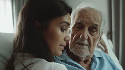 Elderly father and his young daughter having straight talk conversation indoors sitting close on a couch indoors