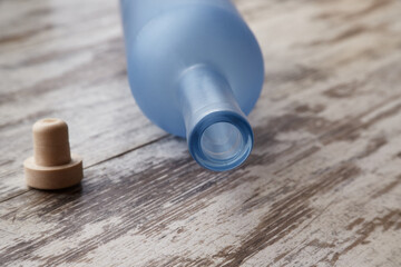 An empty vodka bottle and cork lie on a wooden table, an overturned bottle on a wooden table