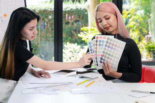 Women point to a color chart for home design. Graphic designers working on color chart at modern office.
