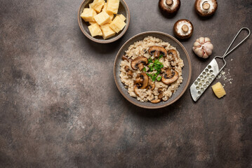 Risotto with mushrooms in a bowl on a dark grunge background. Top view, flat lay, banner.