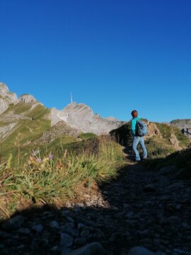 Women hiking in the mountains with backpack looking at santis. Swiss Alps. Appenzellerland.