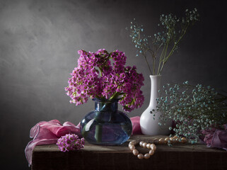 A bouquet of bergenia in a light vase on a dark background. Modern still life with flowers