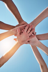 People, team and hands together below for unity, collaboration or synergy on a blue sky background....