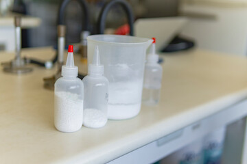 Beaker and applicator bottles with white content placed on table in lab