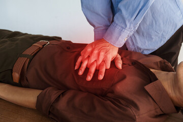 A focused view of a man demonstrating chest compressions on a CPR training class, illustrating...