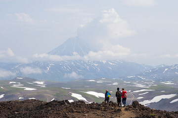 Hikers on a mountain path. View from Gorely volcano to Vilyuchinsky volcano, Kamchatka Krai, Russia. Travel, tourism and hiking on the Kamchatka Peninsula. Beautiful nature of the Russian Far East.