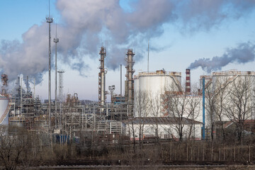 Refinery. Industrial landscape. View of industrial structures and large tanks for petroleum products on the territory of the refinery. Oil refining industry and fuel production. - 794084135