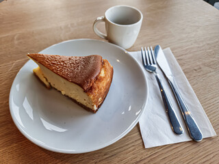 A slice of San Sebastian Cheesecake on a plate with a coffee in a cafe 