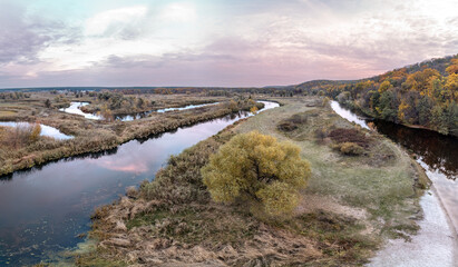 Aerial tree growing on river curve panorama with autumn forest and sunset cloudy sky in Ukraine