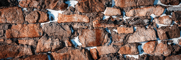Old stone wall covered with snow. Weathered rough masonry surface. Wide panoramic texture for background and design. - 794085377