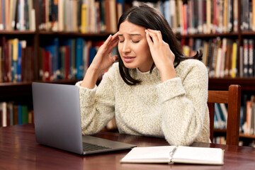 College, laptop or woman with stress headache at campus library for research, planning or homework...