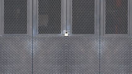 Black metal foldable entrance door background made from carbon steel diamond plate with grid wire mesh in industrial modern loft style, front view with copy space