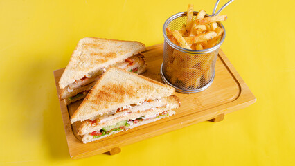 Club sandwich sliced and fries basket on tray