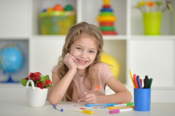 cute girl in the nursery draws at the table