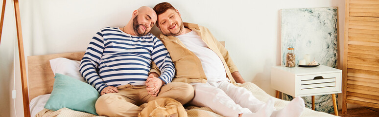 A cheerful gay couple bonding on a bed with their French bulldog. - Powered by Adobe