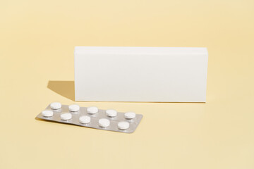 White mockup box and blister with pills of antidepressants, dietary supplements, vitamin D or oral contraceptives on yellow isolated background. Image for your design